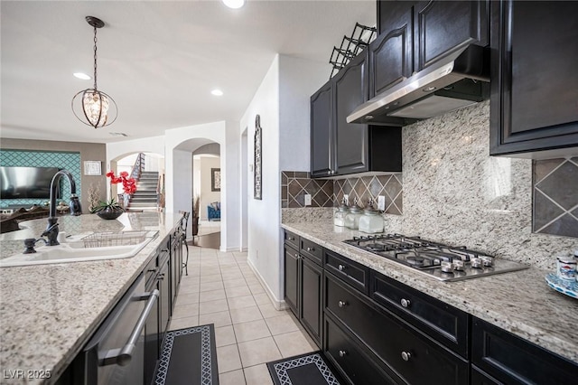 kitchen with stainless steel appliances, light stone countertops, sink, and light tile patterned floors