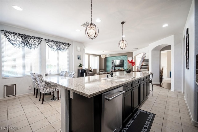 kitchen with pendant lighting, sink, a kitchen island with sink, light tile patterned flooring, and stainless steel dishwasher