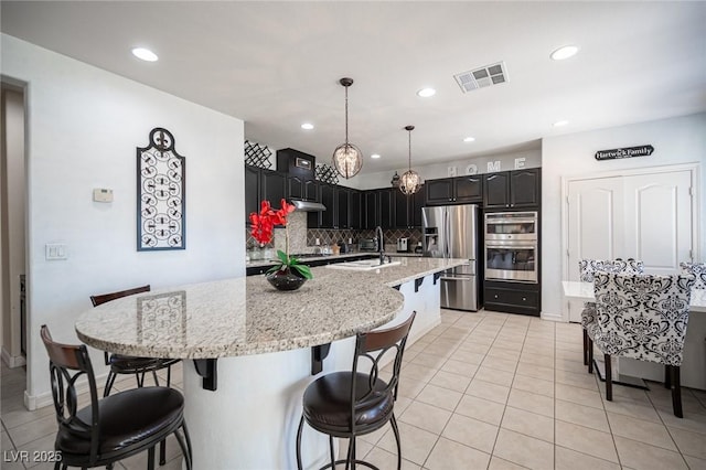 kitchen featuring light tile patterned flooring, sink, pendant lighting, stainless steel appliances, and decorative backsplash