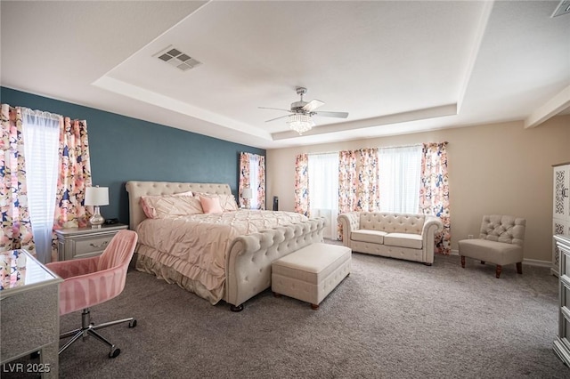 carpeted bedroom featuring a tray ceiling and ceiling fan