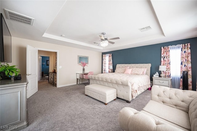 carpeted bedroom featuring ceiling fan and a raised ceiling