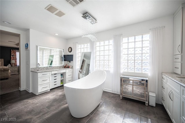 bathroom featuring hardwood / wood-style flooring, a notable chandelier, vanity, and a tub