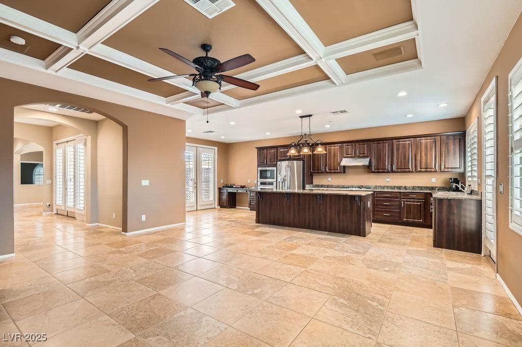 kitchen featuring pendant lighting, a kitchen island, coffered ceiling, and appliances with stainless steel finishes