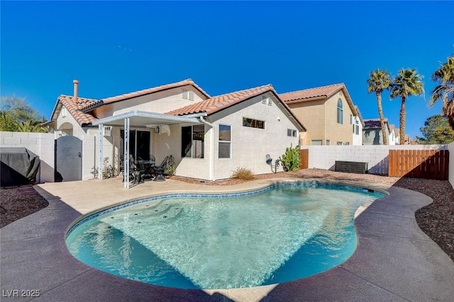 rear view of house with a fenced in pool, a fenced backyard, a tiled roof, a patio area, and stucco siding