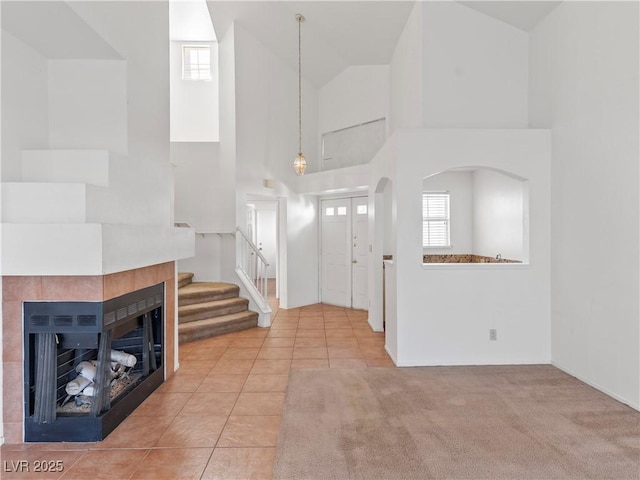 entryway featuring a tiled fireplace, high vaulted ceiling, and light tile patterned floors