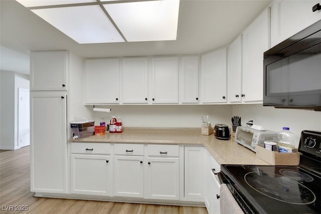 3473 Monte Carlo Dr, Las Vegas, NV 89121 - kitchen featuring electric range oven, black microwave, light wood-style flooring, and white cabinets