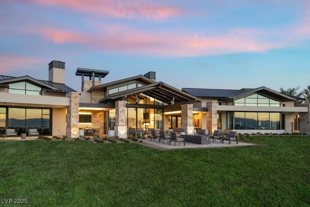 back house at dusk featuring a patio and a yard