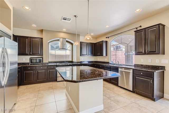 kitchen with light tile patterned flooring, appliances with stainless steel finishes, decorative light fixtures, and a kitchen island