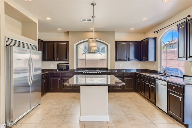 kitchen with a kitchen island, appliances with stainless steel finishes, pendant lighting, sink, and dark brown cabinets