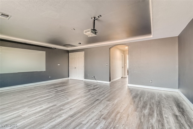 home theater with light hardwood / wood-style floors, a raised ceiling, and a textured ceiling