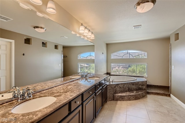 bathroom with a wealth of natural light, tiled bath, tile patterned floors, and vanity