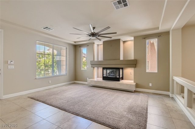 unfurnished living room featuring a raised ceiling, light tile patterned flooring, and ceiling fan