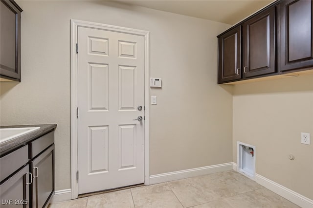 washroom with cabinets, hookup for a washing machine, and light tile patterned floors