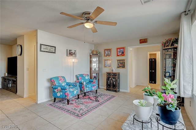 living area featuring light tile patterned floors and ceiling fan