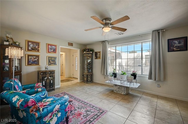 living room with a textured ceiling, ceiling fan, and light tile patterned flooring