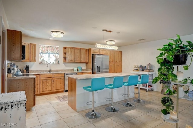 kitchen featuring a kitchen island, decorative light fixtures, sink, light tile patterned floors, and stainless steel appliances