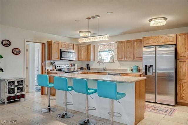 kitchen with stainless steel appliances, decorative light fixtures, a center island, and a kitchen breakfast bar