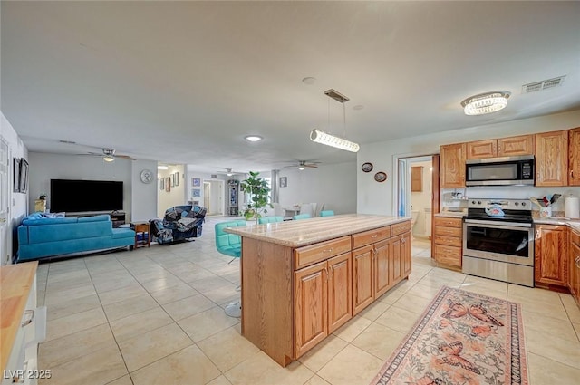 kitchen with hanging light fixtures, a center island, light tile patterned floors, ceiling fan, and stainless steel appliances