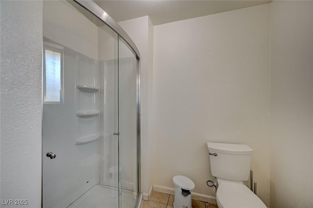 bathroom featuring tile patterned flooring, a shower with shower door, and toilet