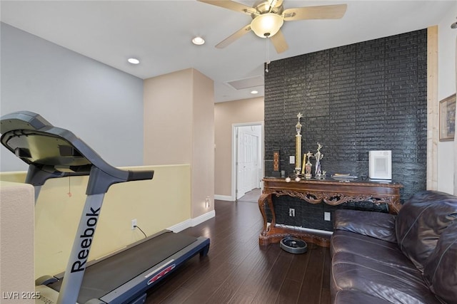 workout area featuring wood-type flooring, ceiling fan, and brick wall