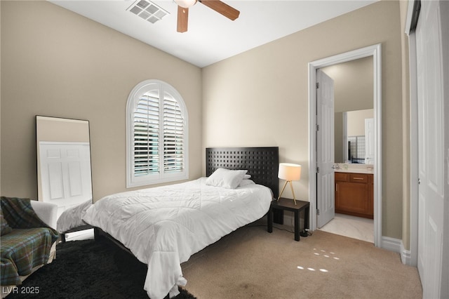 bedroom featuring ceiling fan, ensuite bath, and light carpet