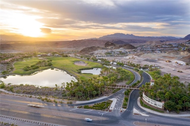 aerial view at dusk featuring a water and mountain view