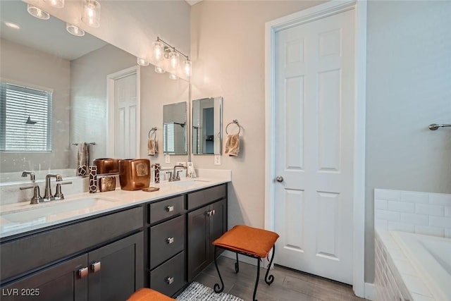 bathroom with tiled tub, vanity, and hardwood / wood-style floors