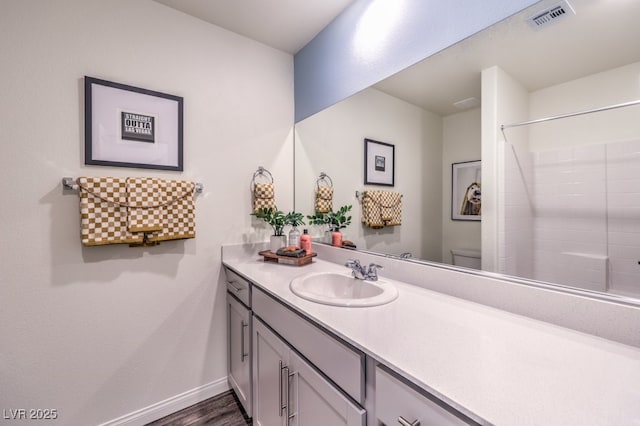 bathroom with vanity, hardwood / wood-style flooring, toilet, and walk in shower