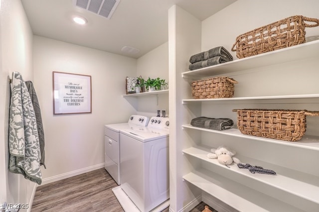 clothes washing area featuring wood-type flooring and washer and clothes dryer