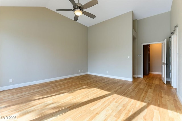 empty room with lofted ceiling, ceiling fan, light wood-type flooring, and baseboards