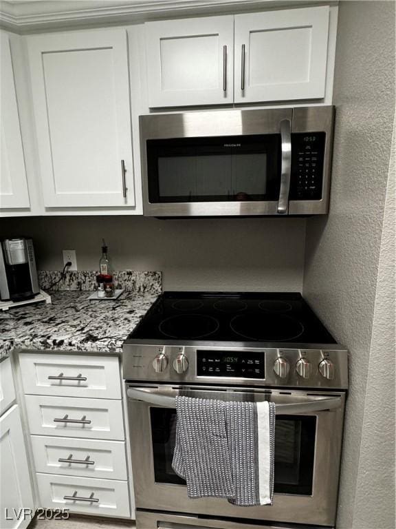 kitchen with appliances with stainless steel finishes, white cabinets, and light stone counters