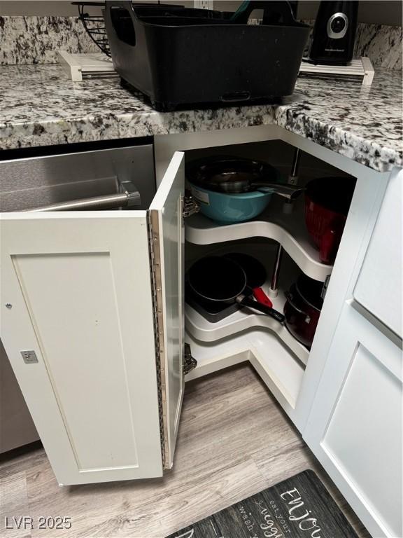 room details featuring white cabinetry, light stone countertops, and light wood-type flooring