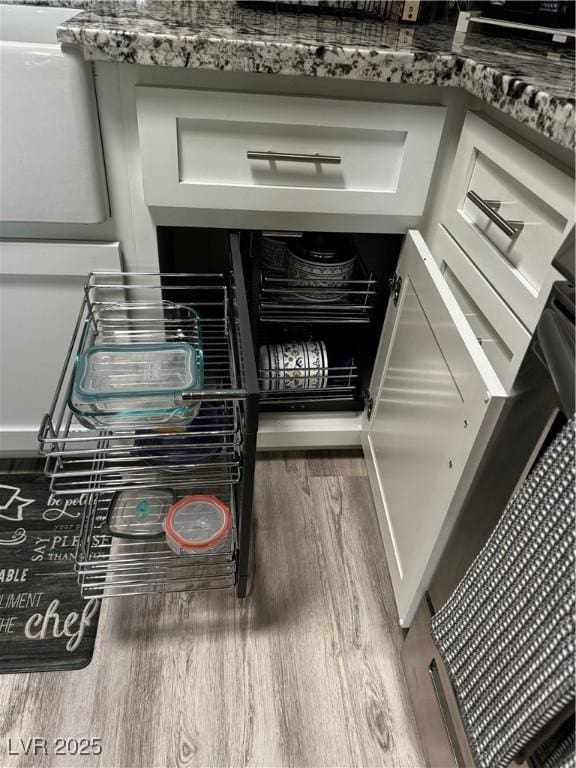 room details with hardwood / wood-style flooring, white cabinetry, and stone countertops