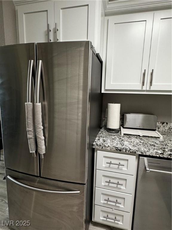 kitchen featuring white cabinetry, light stone counters, and stainless steel refrigerator