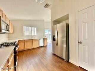 kitchen with appliances with stainless steel finishes, light brown cabinetry, and wood-type flooring