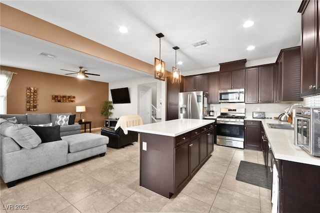 kitchen featuring sink, hanging light fixtures, dark brown cabinets, stainless steel appliances, and a center island