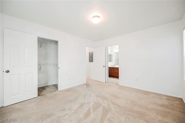 unfurnished bedroom with light colored carpet, electric panel, ensuite bath, and a closet