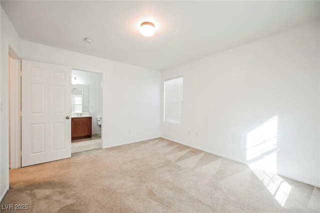 unfurnished bedroom with ensuite bathroom and light carpet