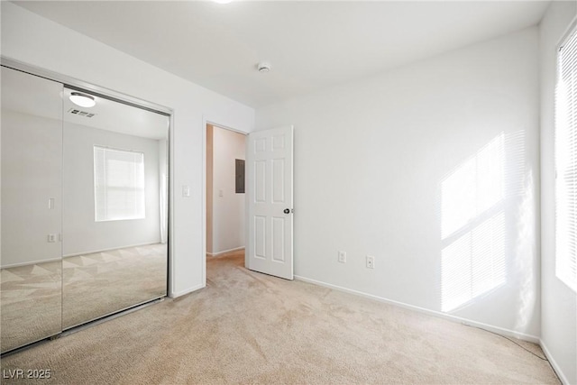 unfurnished bedroom with multiple windows, light carpet, and electric panel