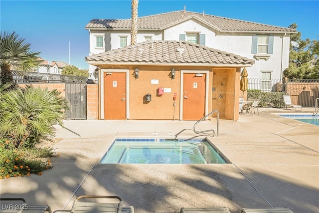 back of property with a swimming pool with hot tub, an outbuilding, and a patio area