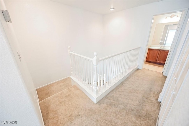 hall featuring sink and light colored carpet