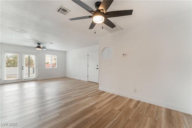 empty room featuring ceiling fan, french doors, a textured ceiling, and light wood-type flooring