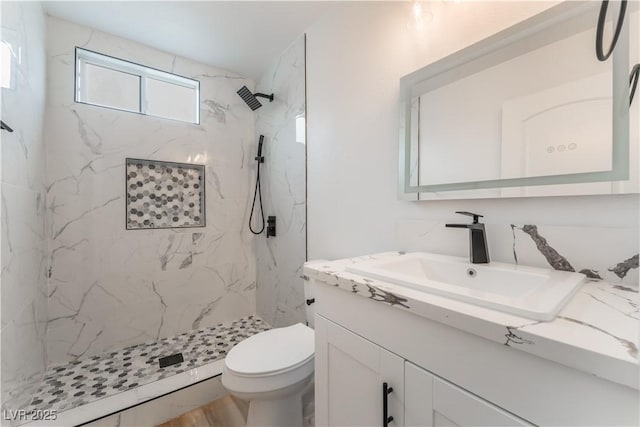 bathroom featuring vanity, tiled shower, and toilet