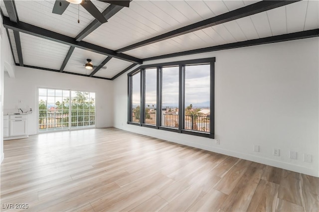 spare room with lofted ceiling with beams, light hardwood / wood-style floors, and ceiling fan