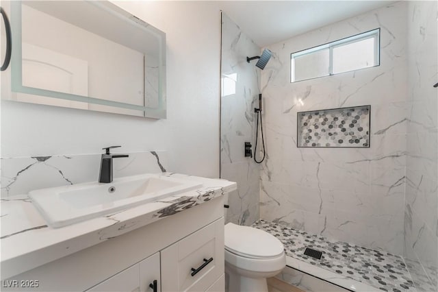 bathroom with vanity, tiled shower, and toilet