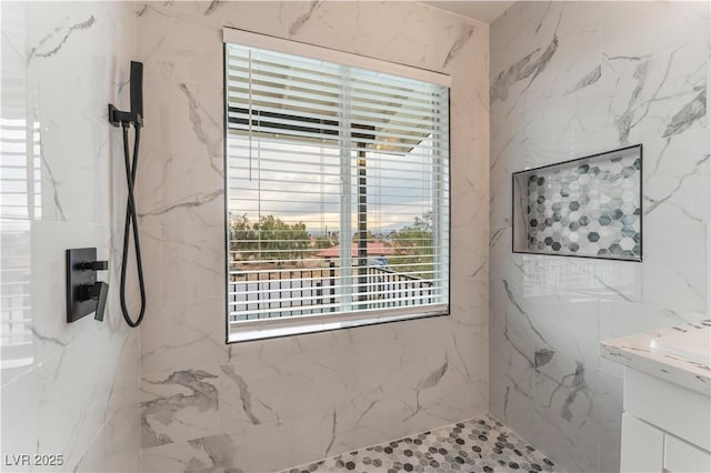 bathroom featuring a tile shower and vanity