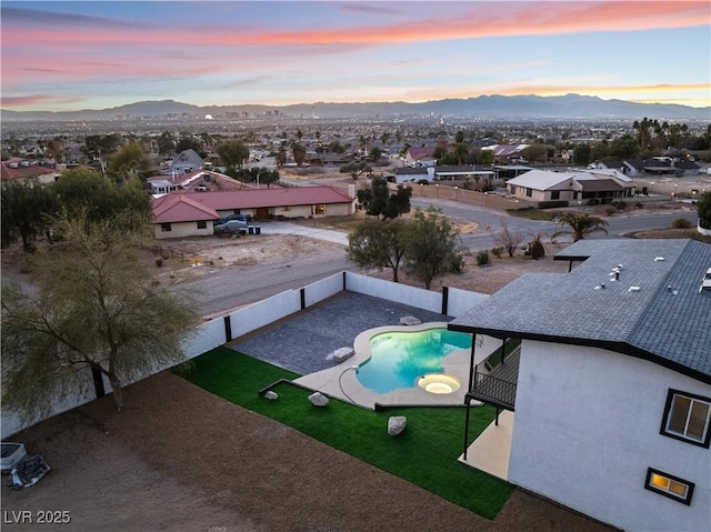 pool at dusk featuring a mountain view and a patio