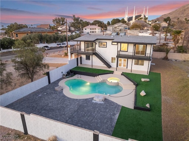 pool at dusk with a yard, a patio, and an in ground hot tub