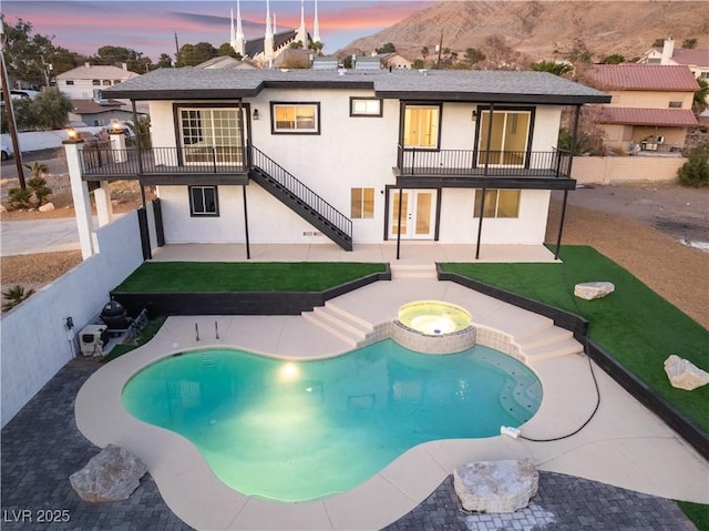 exterior space featuring a swimming pool with hot tub, a patio, and a balcony