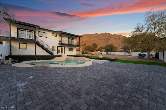 pool at dusk featuring a patio and a mountain view